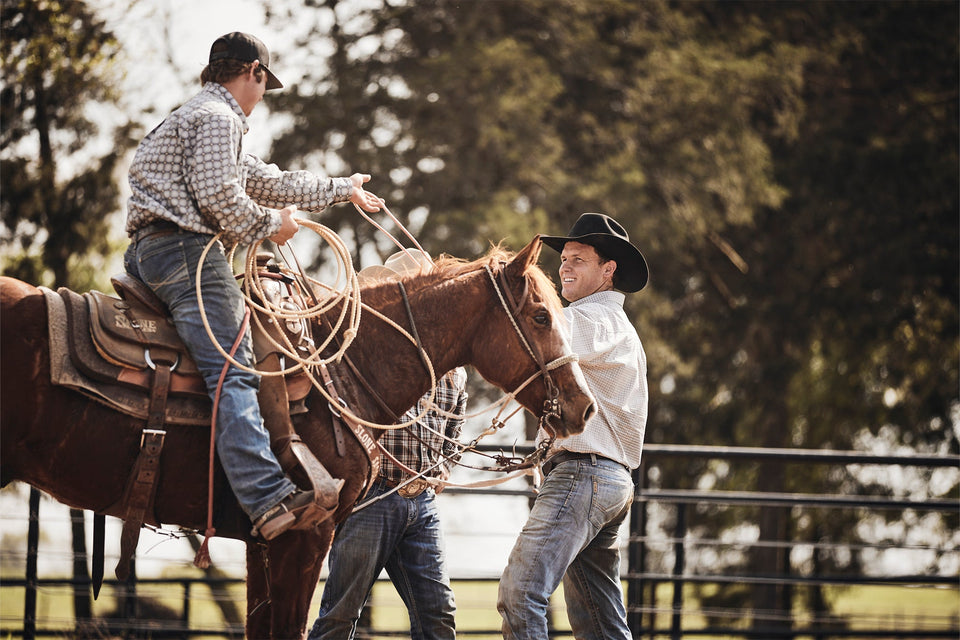 Two men practicing roping at the outdoor arena.