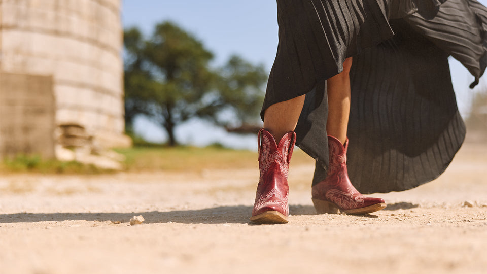 Durango red pony boots on a model wearing a flowing skirt on a a dirt road.