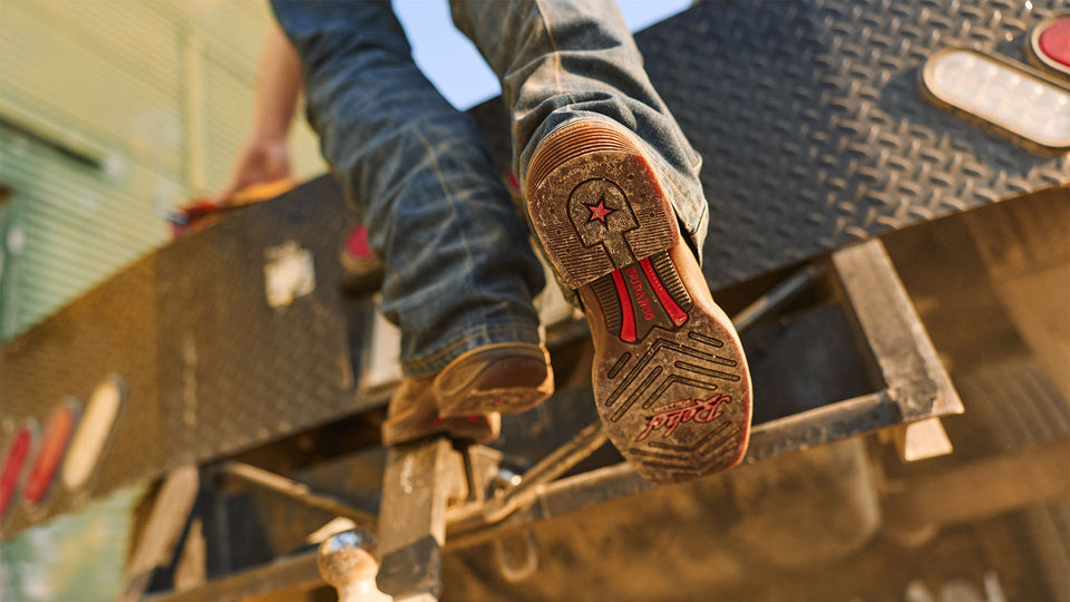 Men’s Durango® Rebel Ultra-Lite™ boot resting on a truck bed, showcasing the rubber outsole and Dually Shank System™ design.