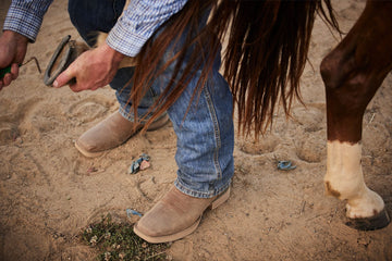 Man picking horse hoof in Durango boots