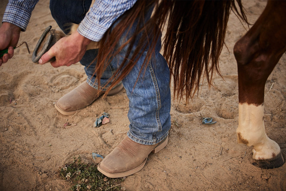 Man picking horse hoof in Durango boots