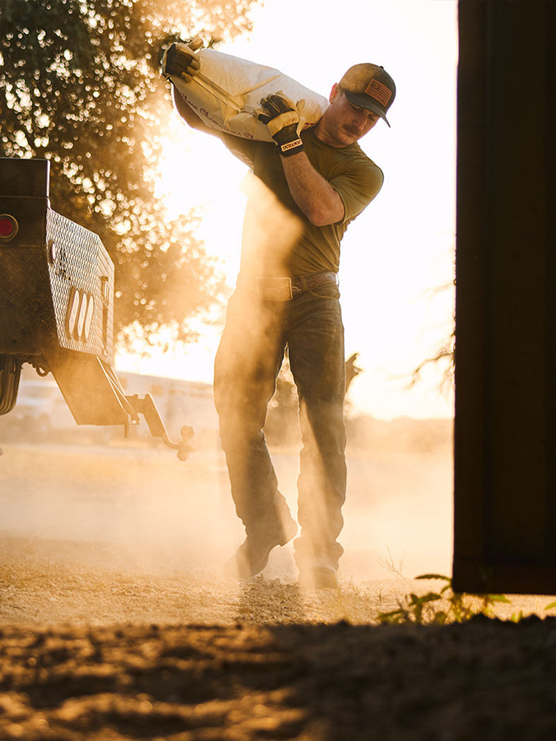 Man carrying a large bag with a vehicle in the background