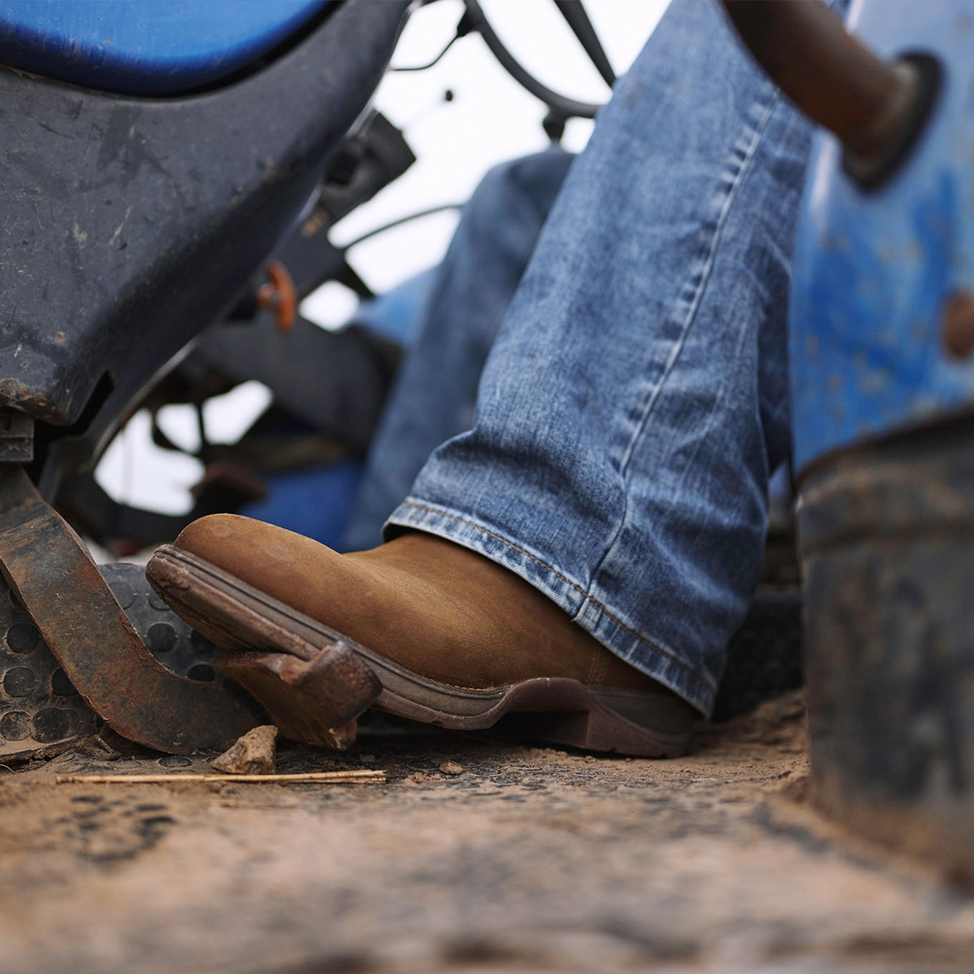 Close-up of brown chelsea boots and blue jeans on a machine