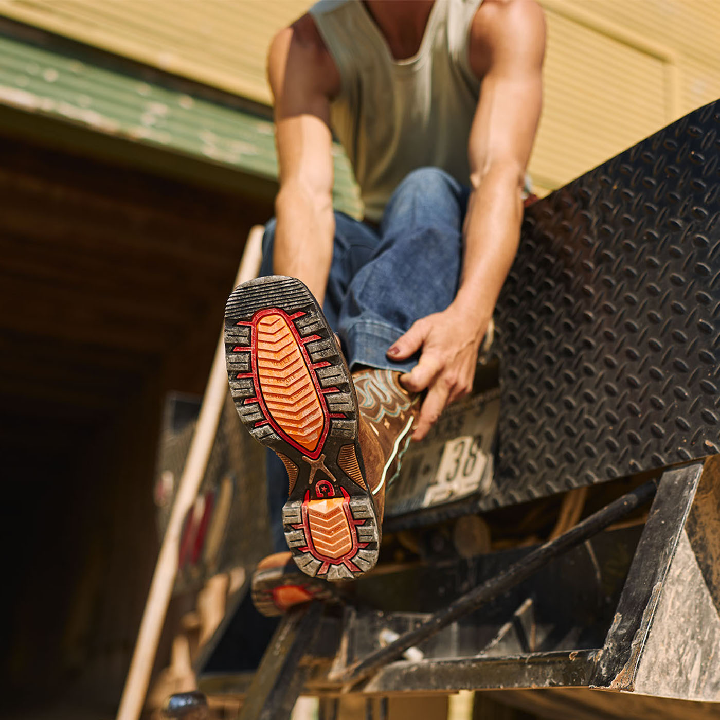 Person wearing brown women's Durango work boots with orange soles on a vehicle, sitting on a step.