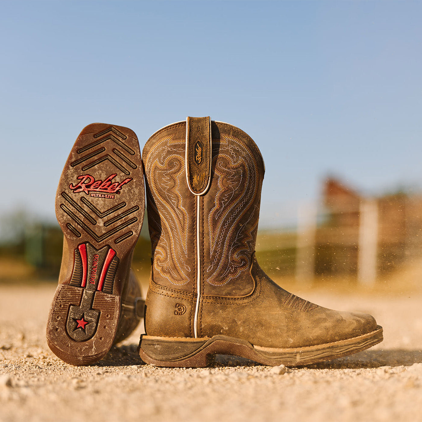Brown cowgirl boots with Rebel Ultra-Lite branding on a gravel road