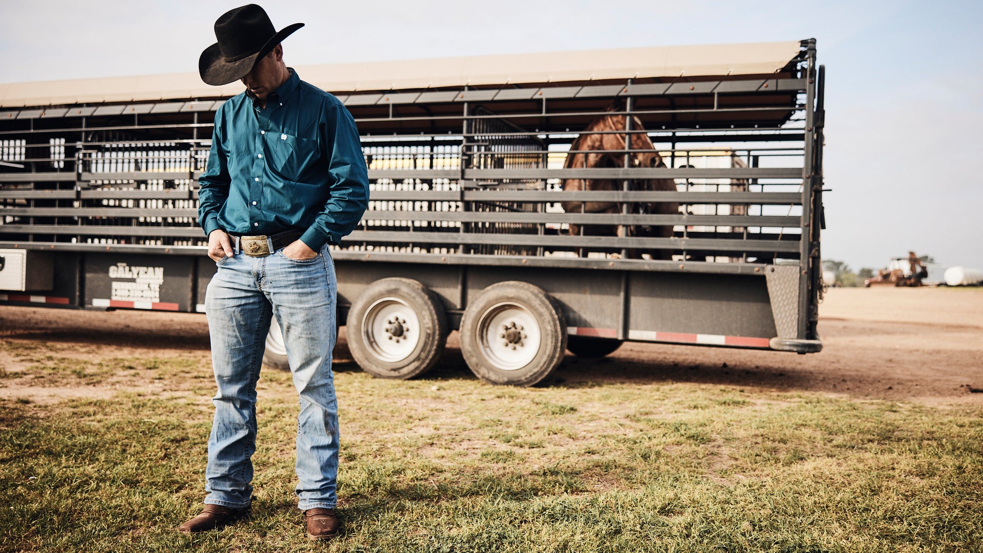 Cowboy standing next to his trailer and horse