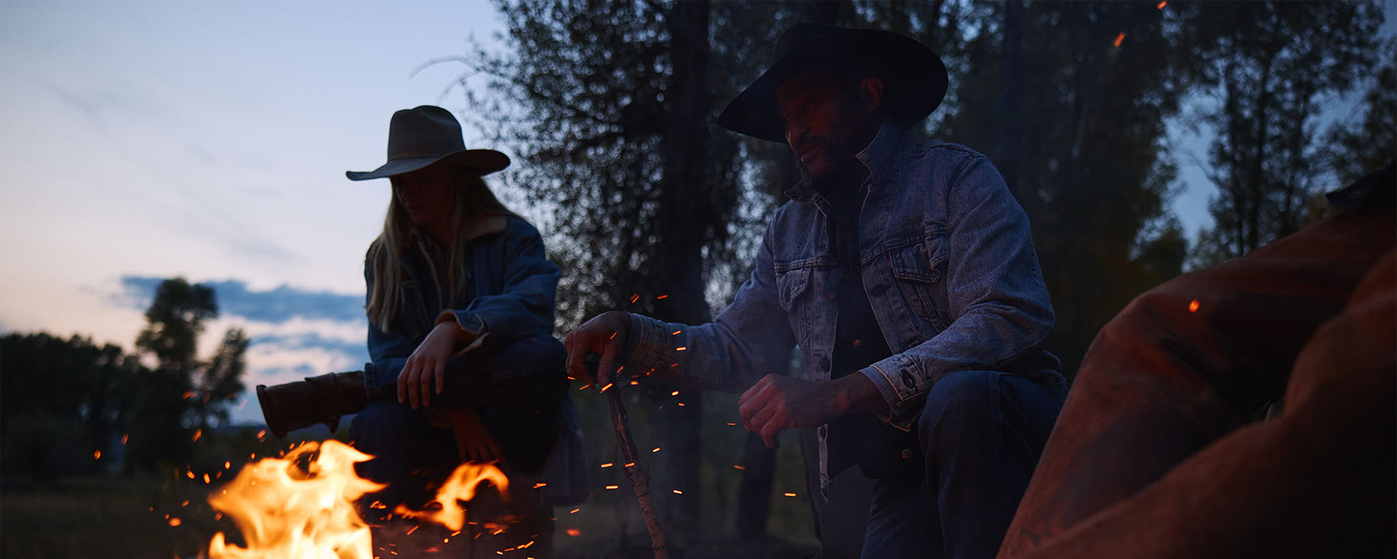 Cowboy and cowgirl gathered around a campfire at Diamond Cross Ranch