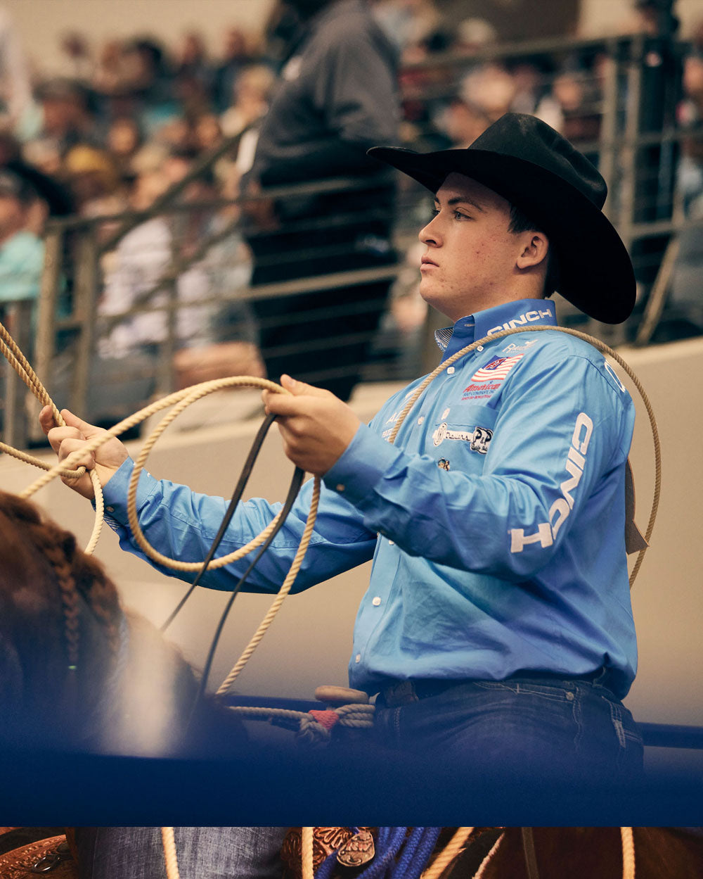 Riley Webb, in a blue shirt holding a lasso at the American Rodeo.